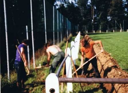 Un groupe de personnes creusent dans la terre près d'une clôture.