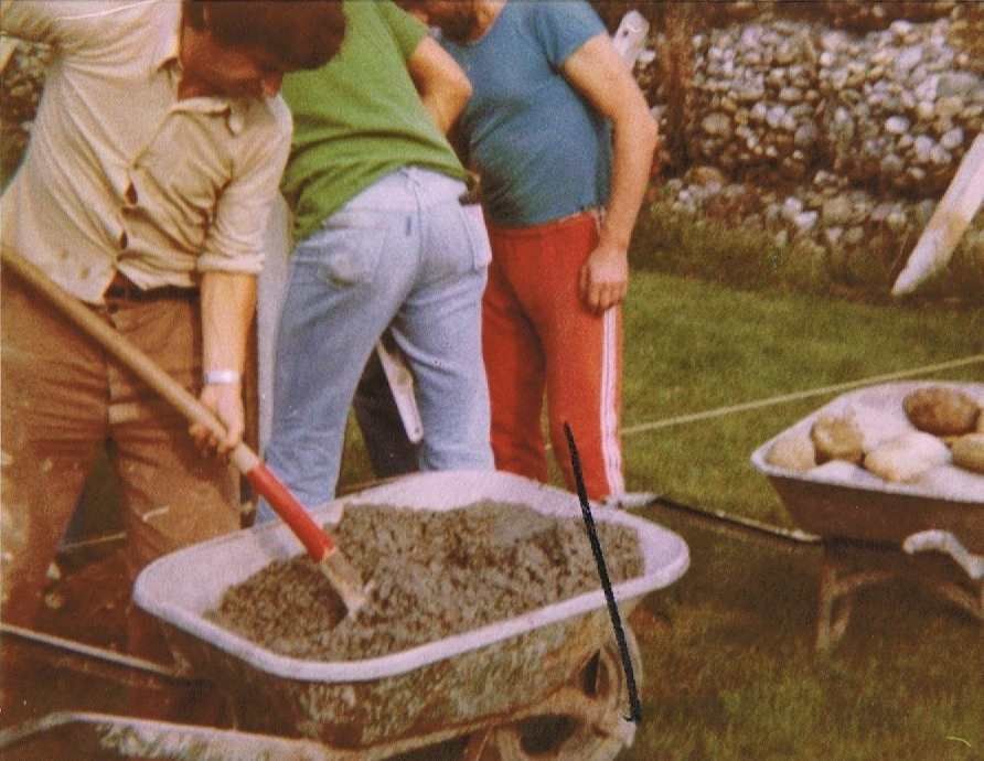 Une brouette remplie de béton est poussée par un groupe de personnes