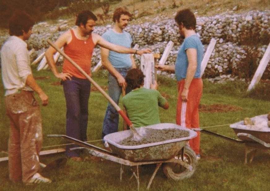 Un groupe d'hommes debout autour d'une brouette pleine de terre