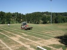 Un tracteur roule de l'herbe sur une piste.