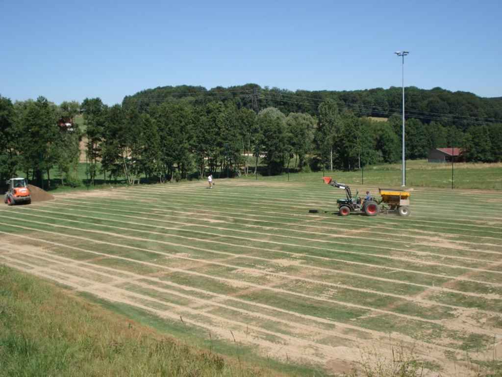 Un tracteur laboure un champ avec des arbres en arrière-plan