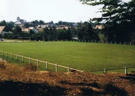 Un terrain de football avec une clôture blanche et des maisons en arrière-plan