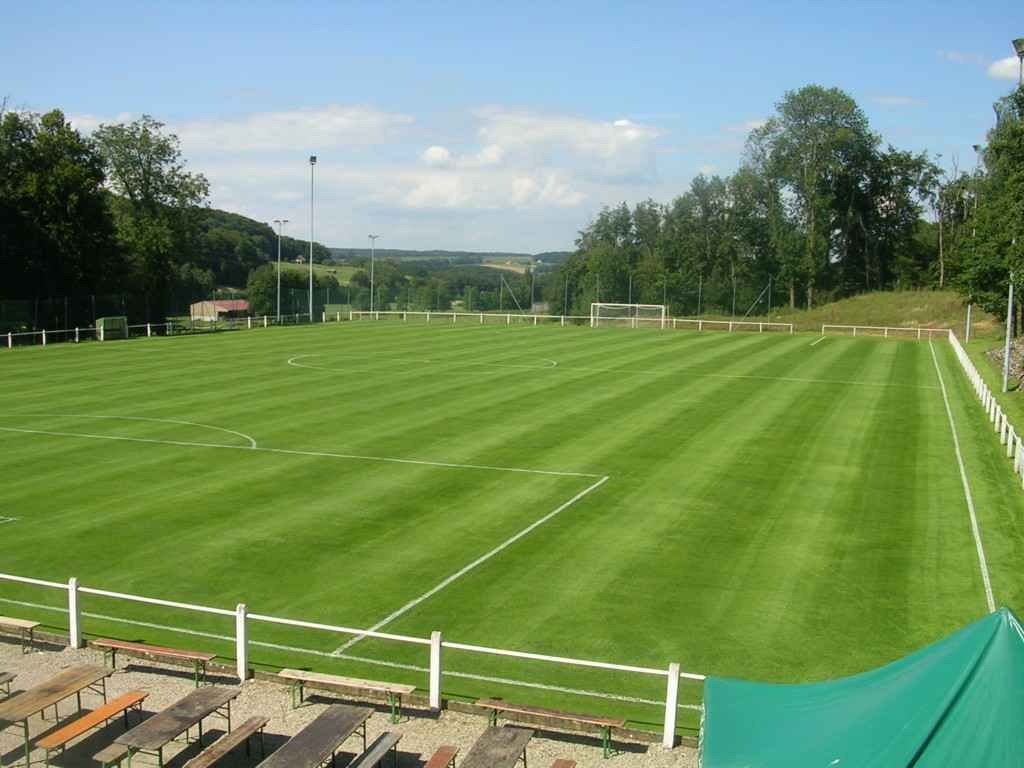 Un terrain de football avec une clôture et des bancs au premier plan
