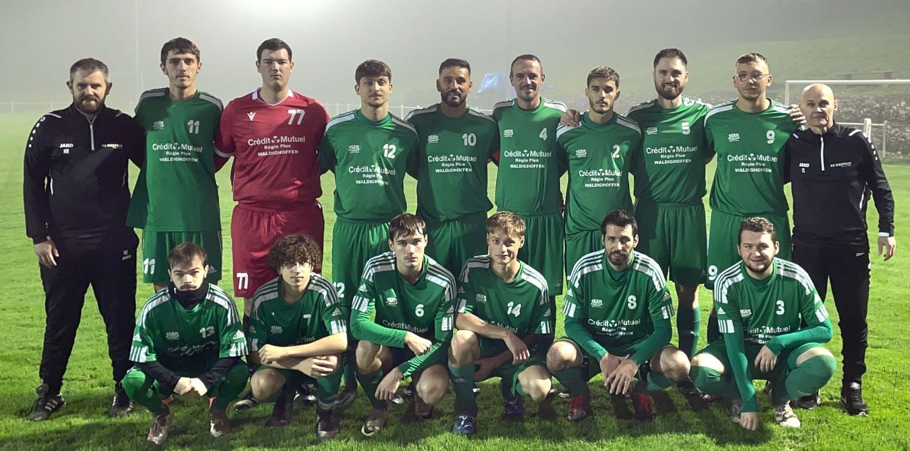 Une équipe de football pose pour une photo sur un terrain.
