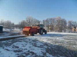 Un tracteur rouge traverse un champ enneigé.