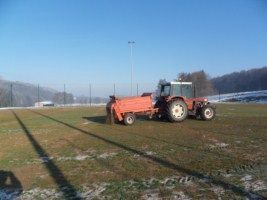 Un tracteur laboure un champ avec une remorque attachée à lui.