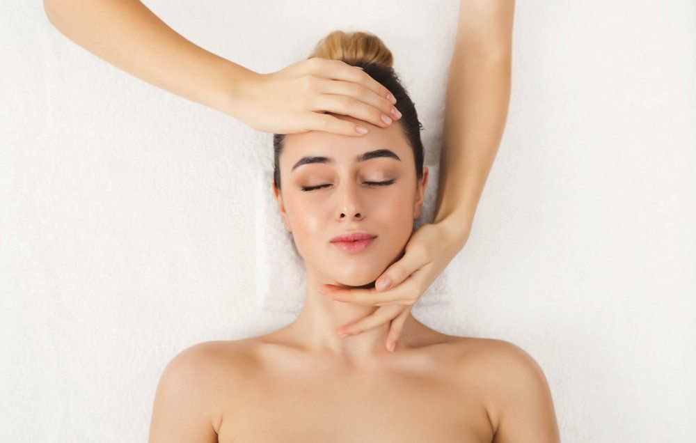 A Woman Is Getting a Head Massage at A Spa — Skin Exquisite Laser & Cosmetic Clinic in Port Macquarie, NSW