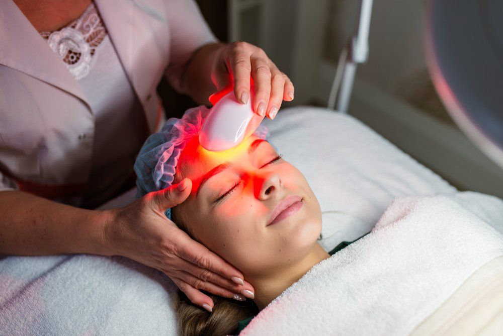A Woman Is Getting a Red Light Treatment on Her Face — Skin Exquisite Laser & Cosmetic Clinic in Port Macquarie, NSW