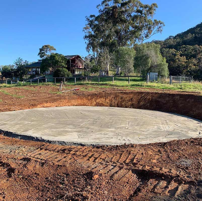 A Large Concrete Circle In The Middle Of A Dirt Field With A House In The Background — Atholyn Earthmovers in Cessnock, NSW