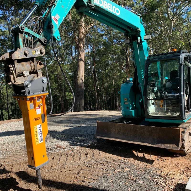A Kobelco Excavator With A Yellow Hammer Attached To It — Atholyn Earthmovers in Maitland, NSW