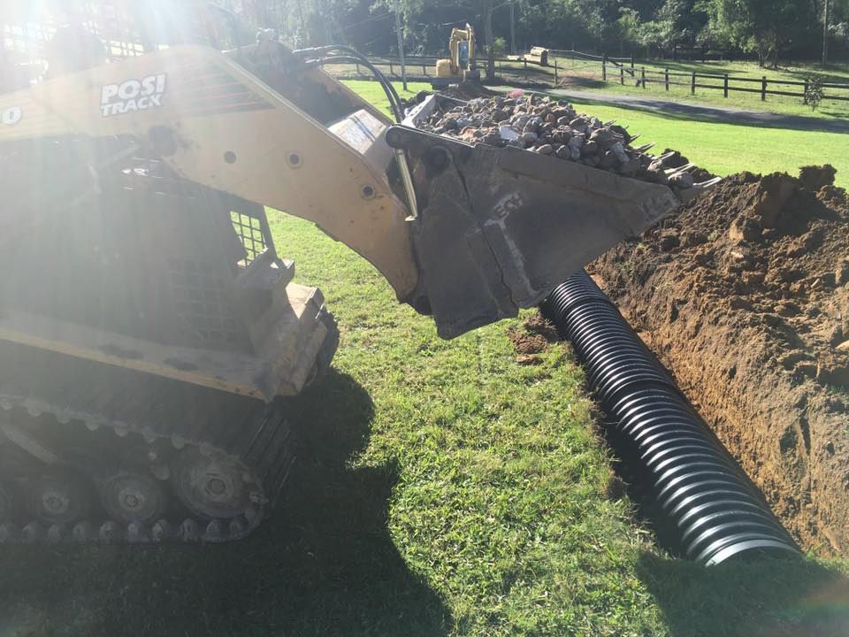 A Bulldozer Is Digging A Hole For A Black Pipe — Atholyn Earthmovers in Singleton, NSW