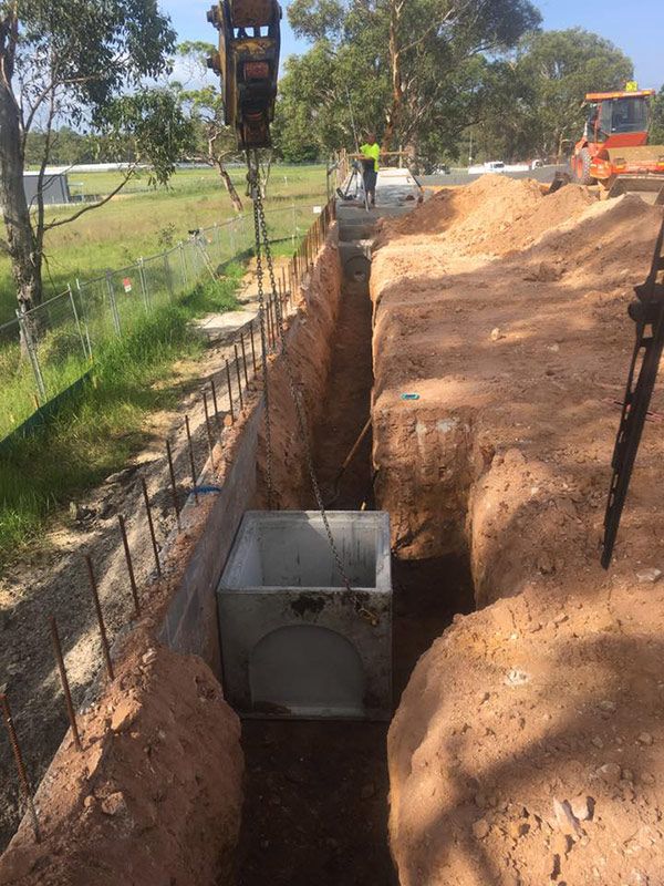 A Large Concrete Box Is Being Lifted Out Of A Hole In The Ground — Atholyn Earthmovers in Cessnock, NSW
