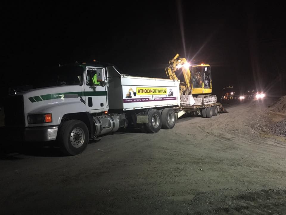 A Dump Truck Is Being Towed By An Excavator At Night — Atholyn Earthmovers in Wyong, NSW