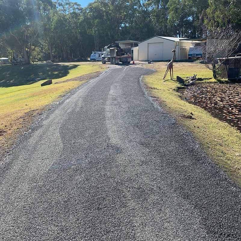 A Dirt Road Going Through A Grassy Area With A House In The Background — Atholyn Earthmovers in Gosford, NSW