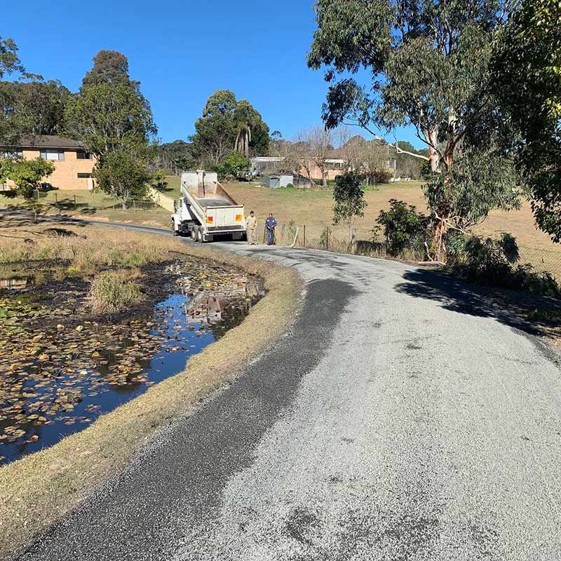 A White Truck Is Parked On The Side Of A Road Next To A Pond — Atholyn Earthmovers in Gosford, NSW
