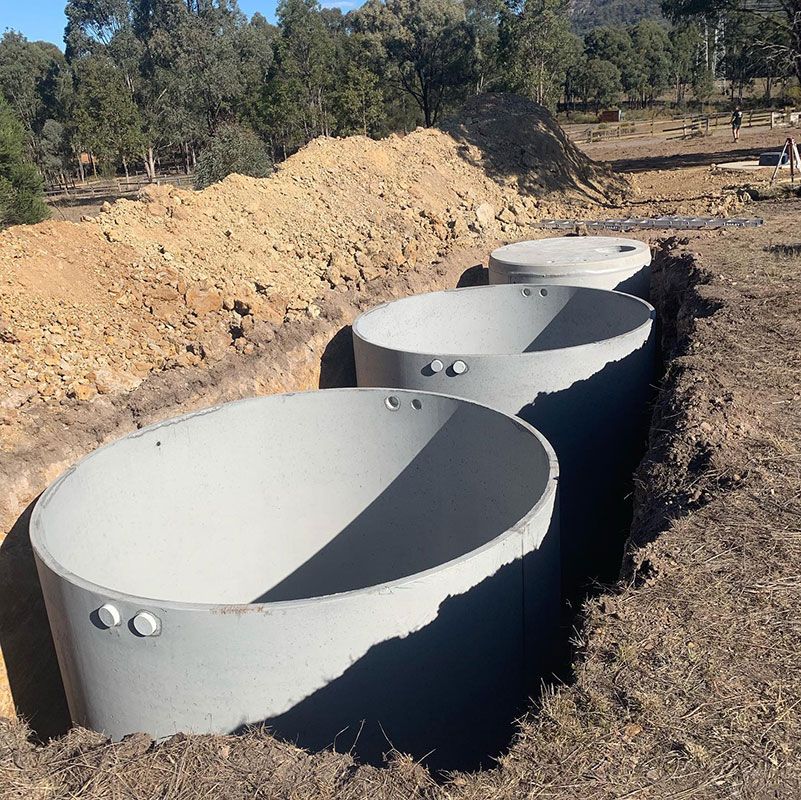 A Row Of Concrete Rings Are Sitting In The Dirt — Atholyn Earthmovers in Cessnock, NSW