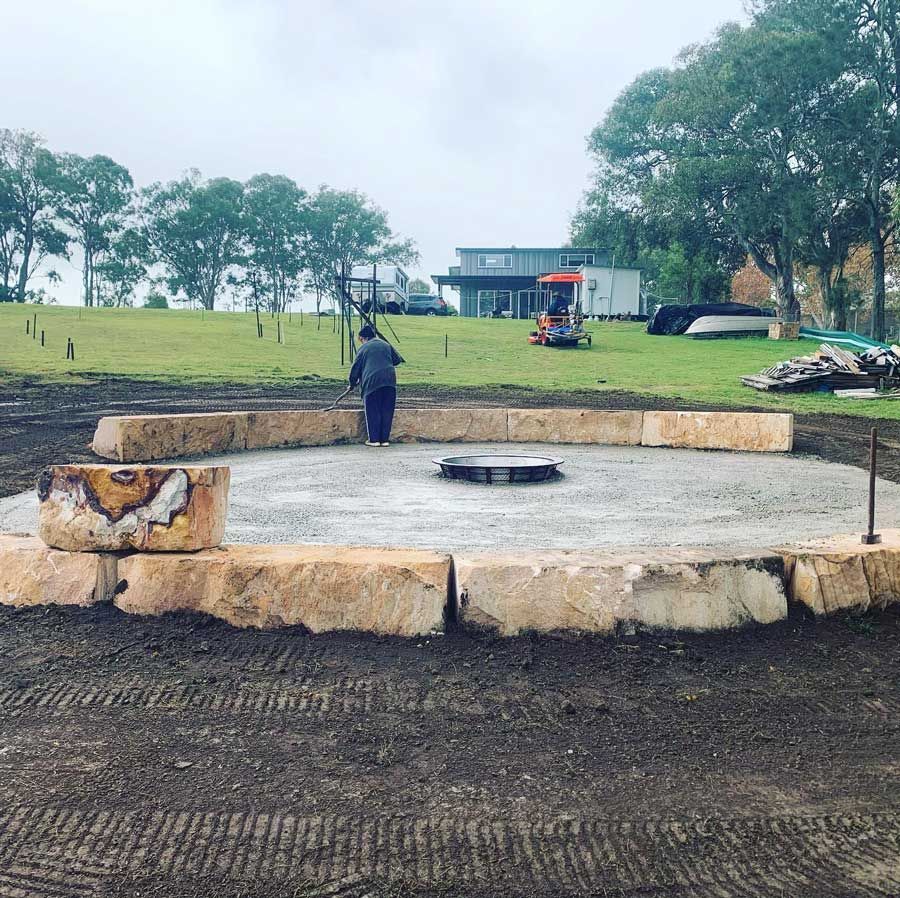 A Man Is Standing In The Middle Of A Concrete Septic Tank In A Field — Atholyn Earthmovers in Maitland, NSW