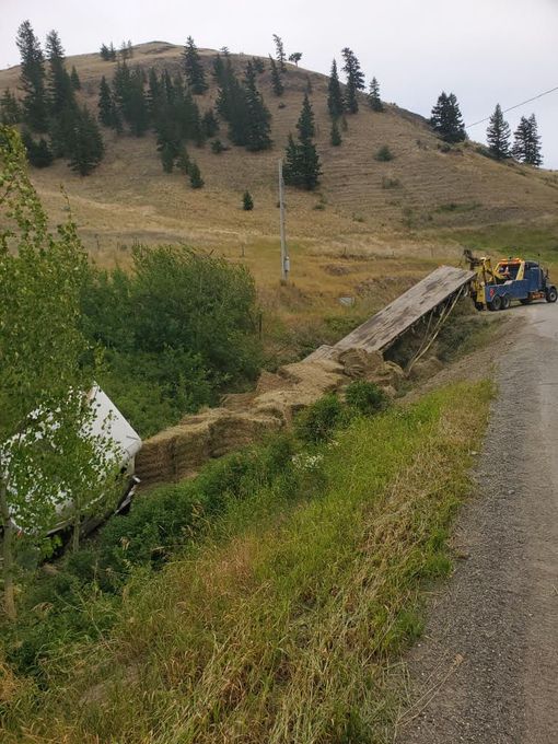 Truck wrecked in roadside ditch with hay spilled onto grass