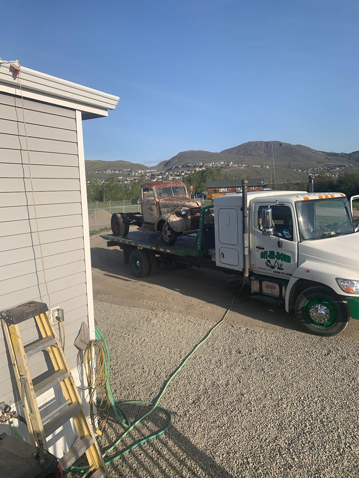 junk vehicle on the back of Get-Er-Done Towing flatbed