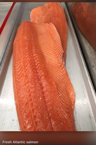 A tray of fresh atlantic salmon is sitting on a table.