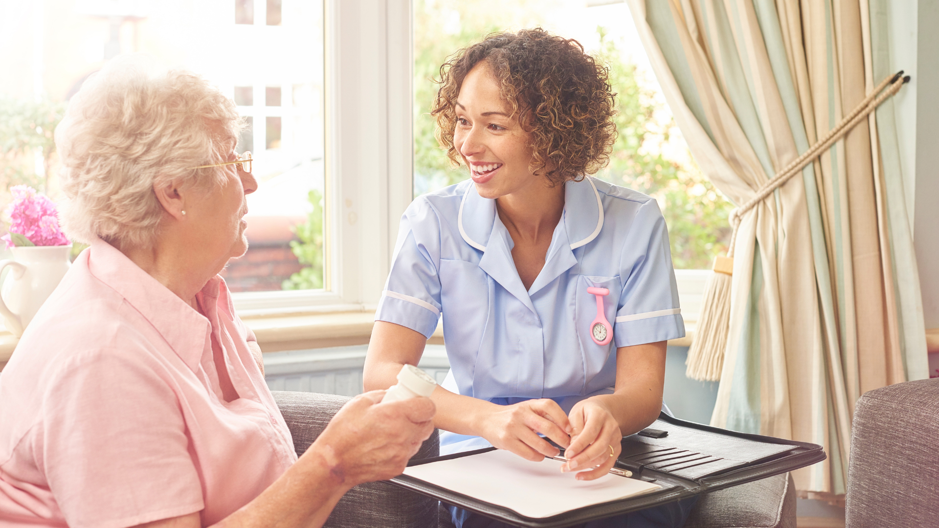 Nurse assisting an older person with medication in a well-lit room.