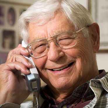 older man smiling on the phone