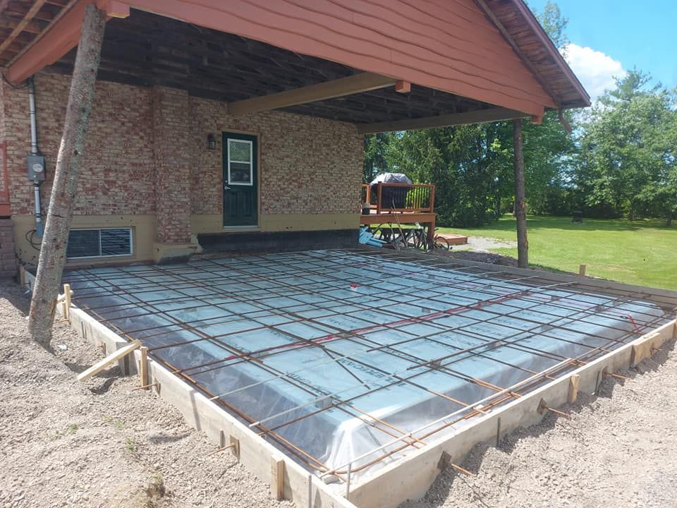 Une dalle de béton est en train d'être coulée devant une maison.