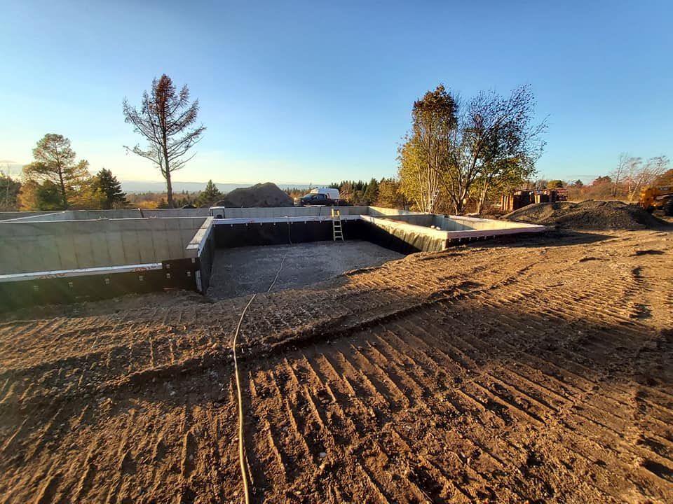 Une grande structure en béton est en cours de construction dans un champ de terre.