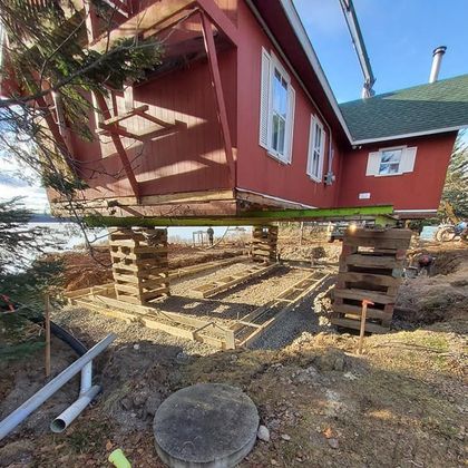 Une maison rouge est soulevée par une grue