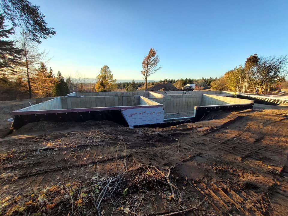 Une grande fondation en béton se trouve au milieu d'un champ de terre.