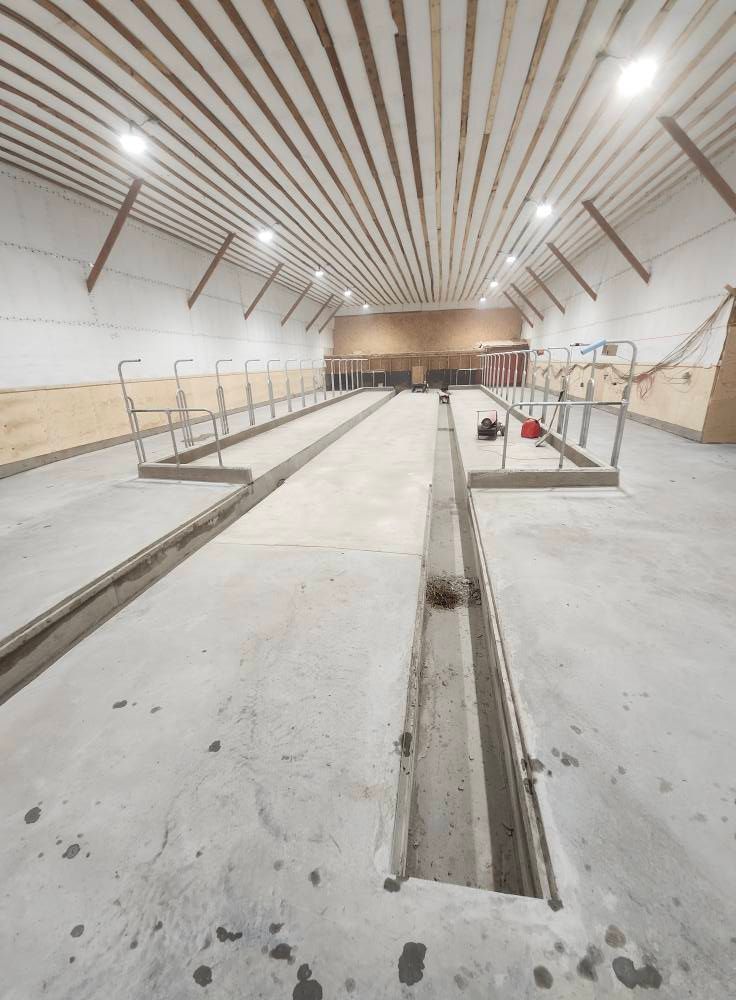 Une grande pièce avec un sol en béton et un plafond en bois.