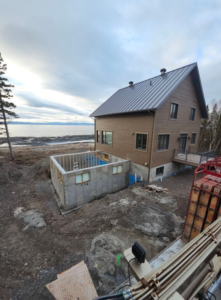 Une grande maison est en construction au milieu d'un champ de terre.