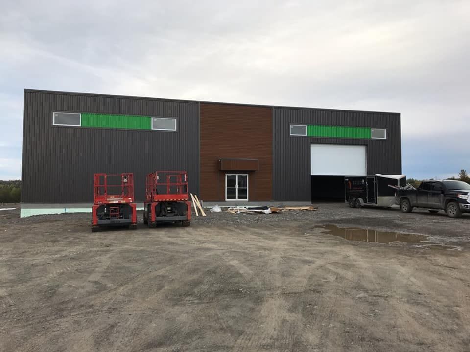 Deux élévateurs à ciseaux sont garés devant un grand bâtiment.