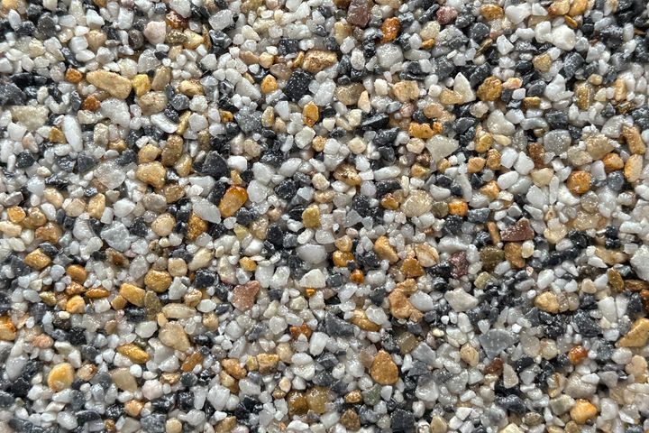 A close-up view of small, multicolored decorative pebbles in shades of white, gray, black, and tan.