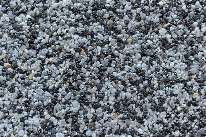 A close-up of a textured surface covered in a mix of small black, gray, and white gravel stones.