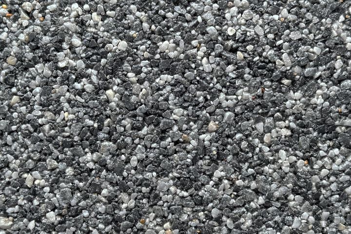 A close-up texture of small, crushed gravel stones in shades of black, gray, and white.