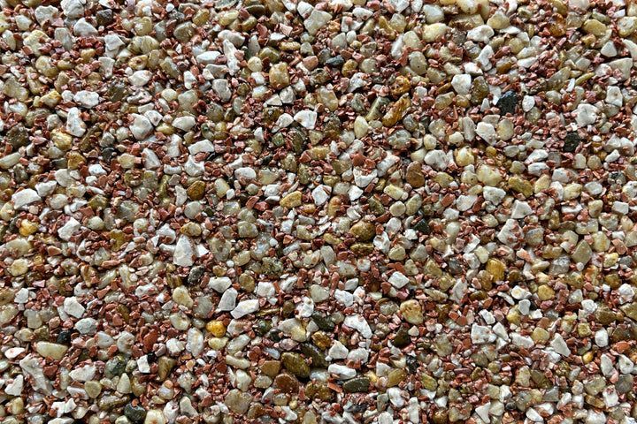 A close-up of mixed aggregate flooring or resin-bound gravel with a blend of red, white, and tan stones.