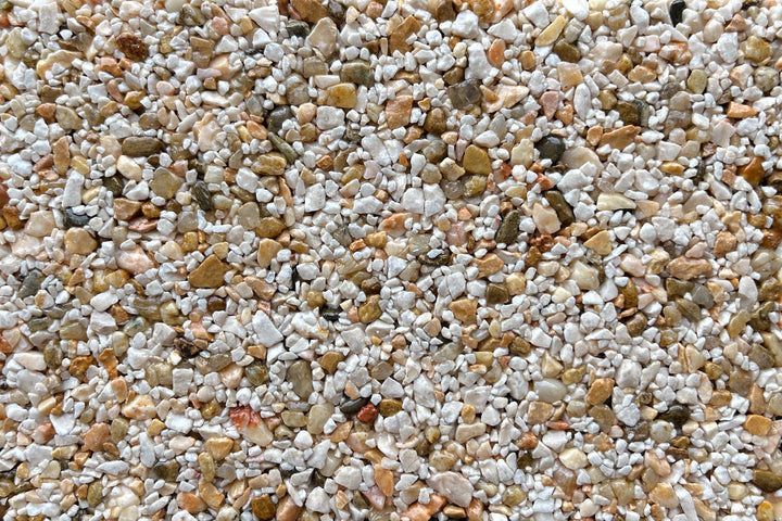 A close-up view of small, multicolored pebbles and gravel in shades of white, tan, gray, and brown.