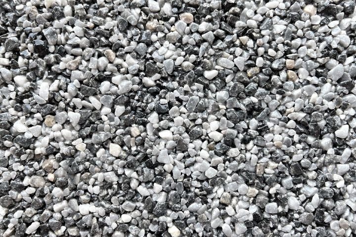 A close-up of a mixture of small, smooth pebbles in shades of gray, white, and black.