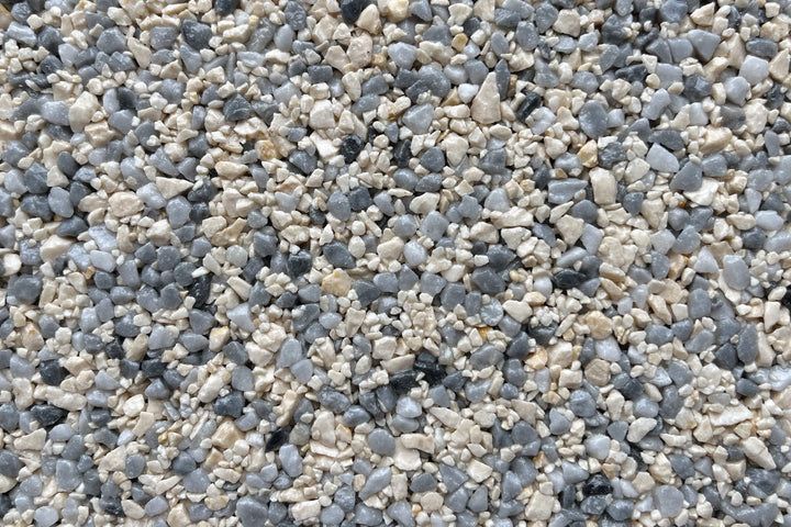 A close-up view of small, multicolored decorative gravel stones in shades of light gray, dark gray, and beige.