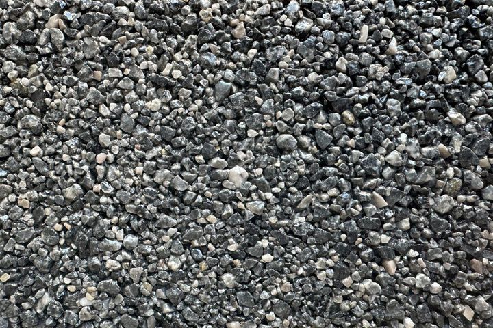 A close-up view of small, multicolored gravel stones in shades of gray, black, and white.