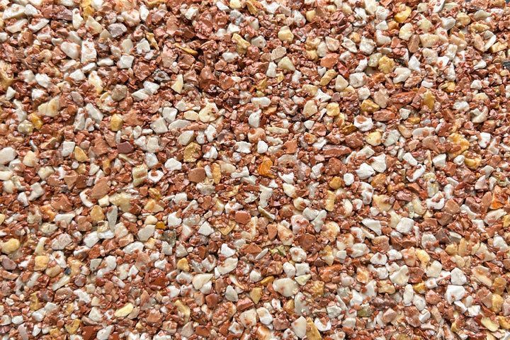 A close-up texture of small, multi-colored gravel stones in shades of brown, tan, and white.