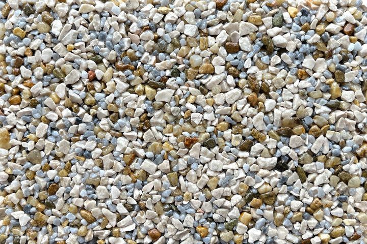 A close-up of small, multi-colored gravel stones in shades of white, gray, tan, and brown.