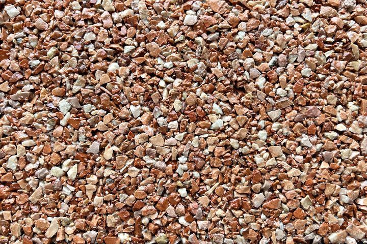 Close-up of small, angular gravel stones in mixed shades of red, brown, and off-white.