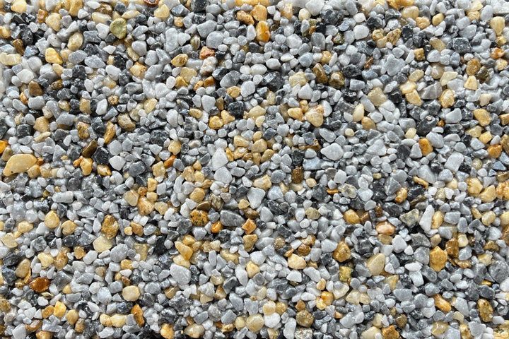 A close-up of mixed decorative gravel in shades of grey, white, and golden-brown.