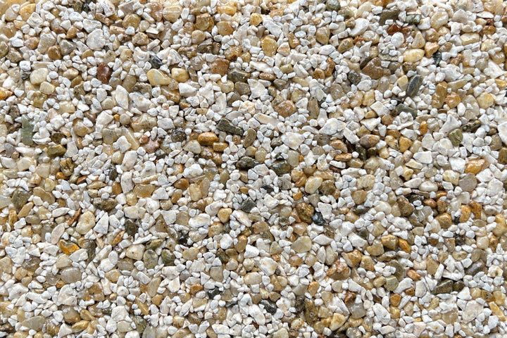 A close-up view of small, multi-colored pebbles in shades of white, tan, gray, and brown.