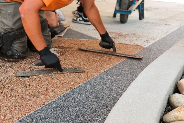 Worker laying gravel and edging stones for a landscape border