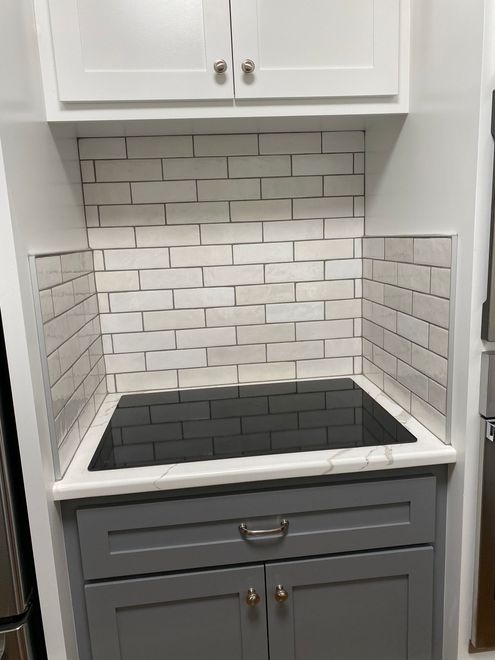 A stove top oven is sitting on top of a gray cabinet in a kitchen.