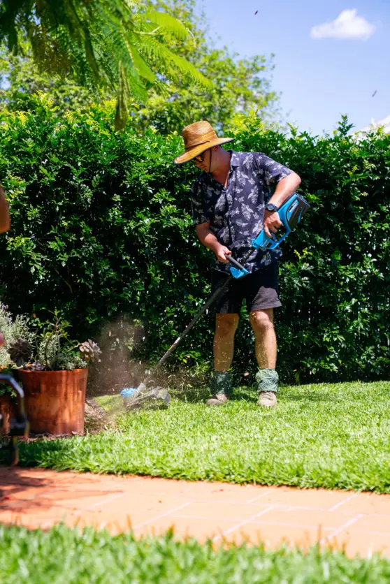 A man is using a lawn mower to cut the grass in a backyard.