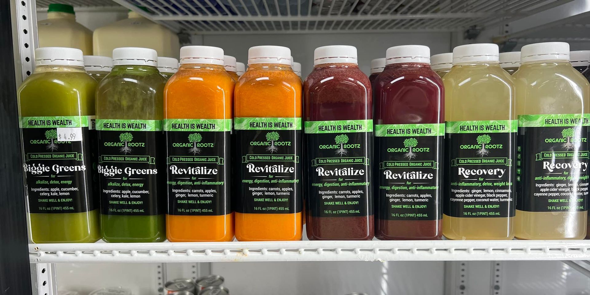 bottles of juice are lined up on a shelf in a refrigerator .